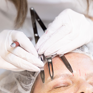 Microblading Nahaufnahme der Ausmessung und Vorzeichnung auf den Augenbrauen mittels Zirkel
